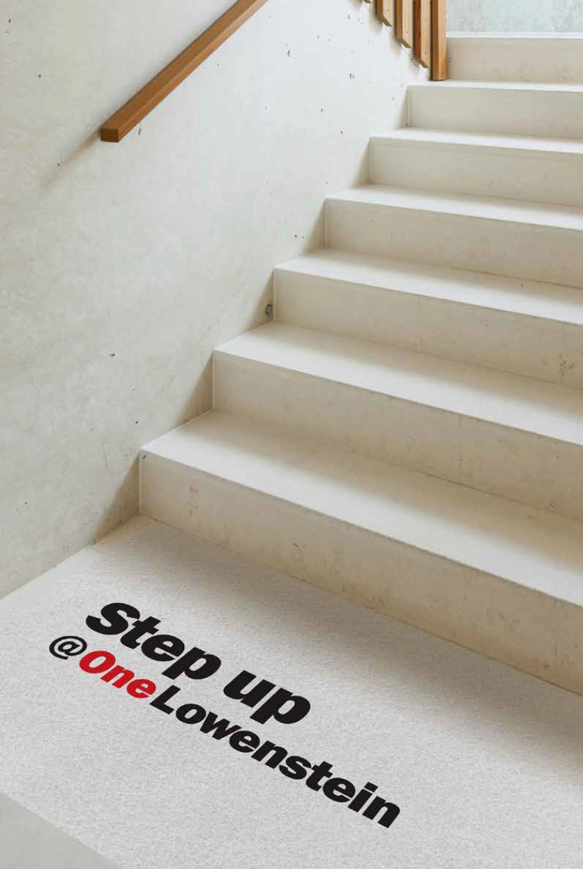 Modern stairs with the saying Step Up @OneLowenstein at the foot of the stairs