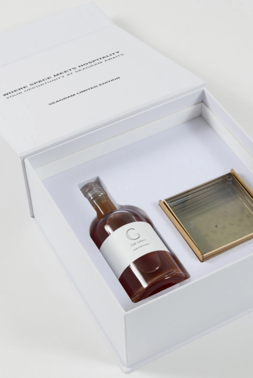 A bottle of the Grill whiskey in a white box
